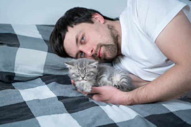 istock Man Lying on Bed and Caring for Kitten 1345374387
