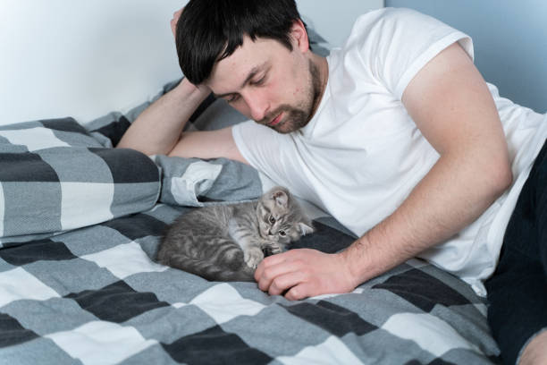 istock Man Lying on Bed and Caring for Kitten 1345374676