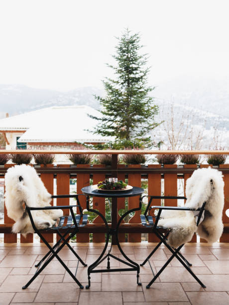 istock Winter balcony with coffee table, cozy chairs covered with white fur and splendid snow-covered mountains view. Winter vacation 1345375924