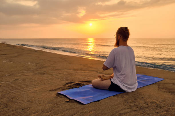 istock Man sits in lotus position at beach 1345375946