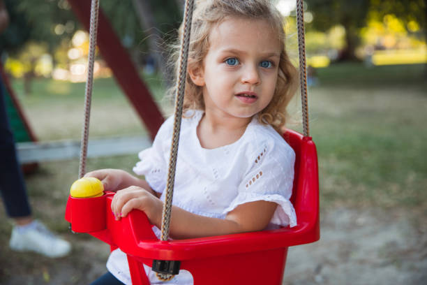 Curious young girl in a swing at the park
