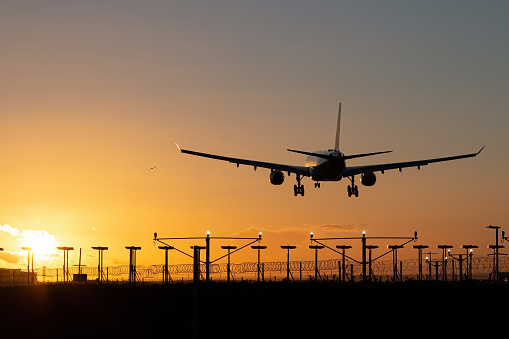 Aterrizaje del avión de pasajeros durante la puesta del sol. photo