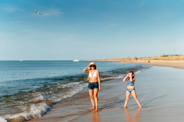 Mother and daughter playing frisbee at the beach Multiracial family enjoying a day at the beach family beach vacations travel stock pictures, royalty-free photos & images