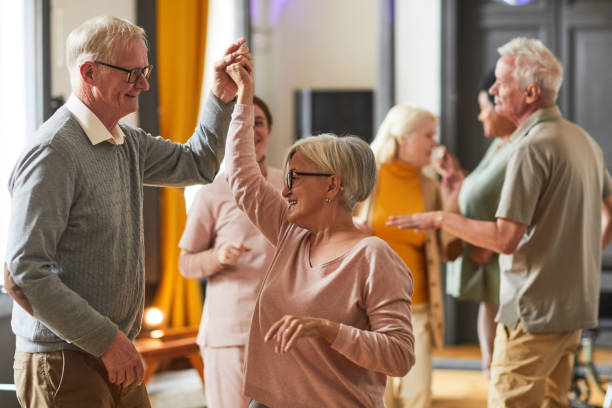 Senior People Dancing in Retirement Home Group of smiling senior people dancing while enjoying activities in retirement home, copy space dancer stock pictures, royalty-free photos & images