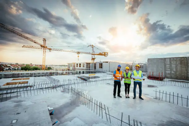 Employees working on construction site, wearing protective equipment and discussing next construction phase