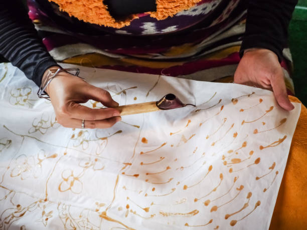 Batik, the Indonesian traditional fabric A woman's right hand is drawing batik pattern with a tjanting, a special tool to flow the ink on the fabric batik indonesia stock pictures, royalty-free photos & images