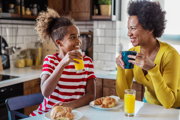 istock Mother and daughter talking in the kitchen while having breakfast 1345390750