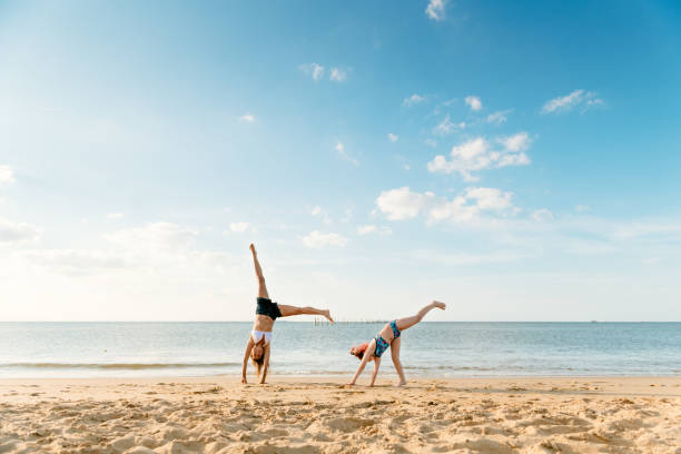 mãe e filha fazendo carrinhos na praia - acrobatic activity - fotografias e filmes do acervo