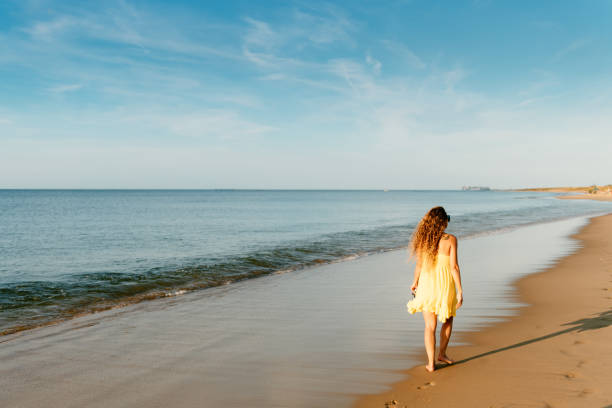 istock Woman walking by the sea 1345391535