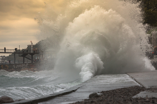 Huge stormy waves crashing near the city embankmen. Big sea wave splash. Giant waves on a stormy day in Yalta. Power of nature, storm concept