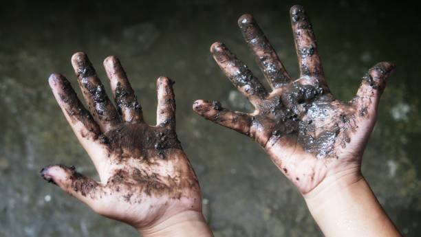 istock child's dirty hands. black mud on the palms with blur background 1345396531