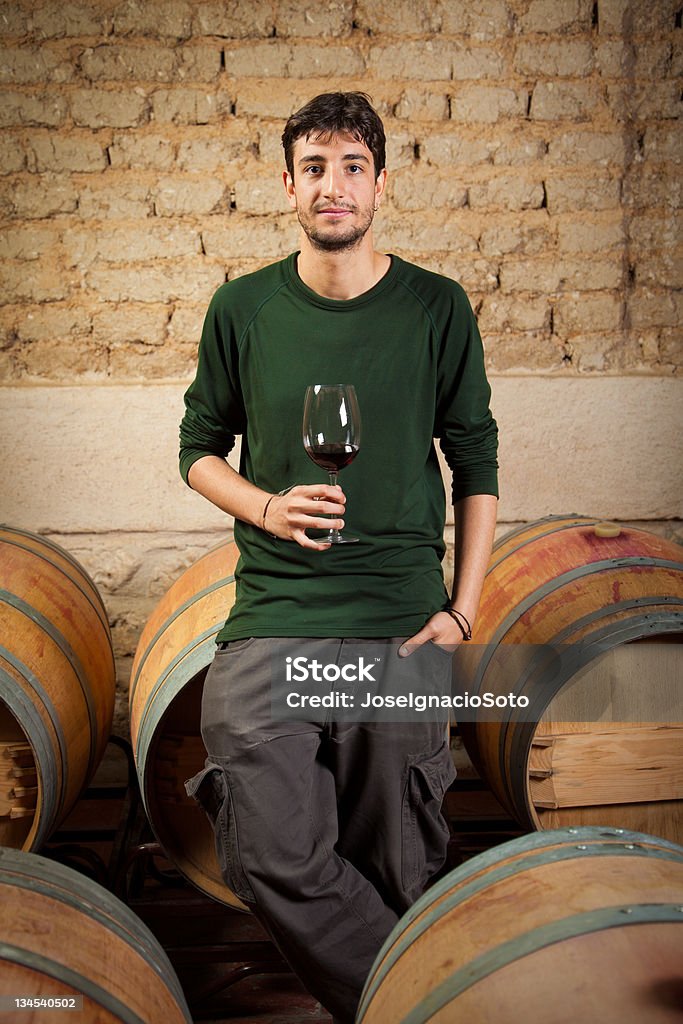 Young vintner'degustación de vino tinto en una antigua bodega - Foto de stock de Catavinos libre de derechos