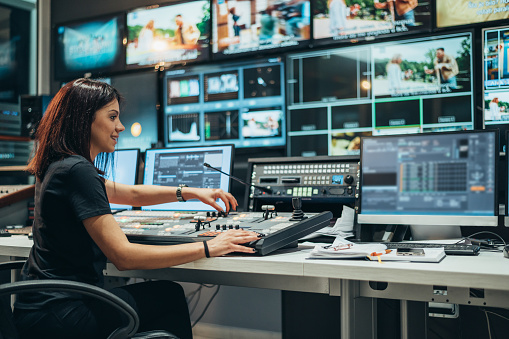 Joven y hermosa mujer trabajando en una sala de control de transmisión en una estación de televisión photo