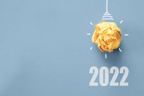 istock 2022 Yellow paper light bulb on blue background, innovative business vision and resolution concept 1345411262