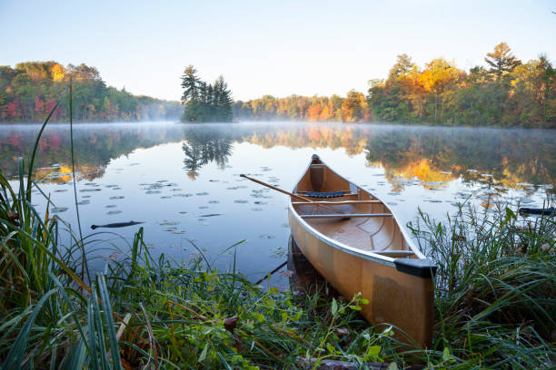 Yellow canoe on shore of calm lake with island at sunrise during autumn Yellow canoe on shore of calm lake with island at sunrise during autumn ultralight photos stock pictures, royalty-free photos & images