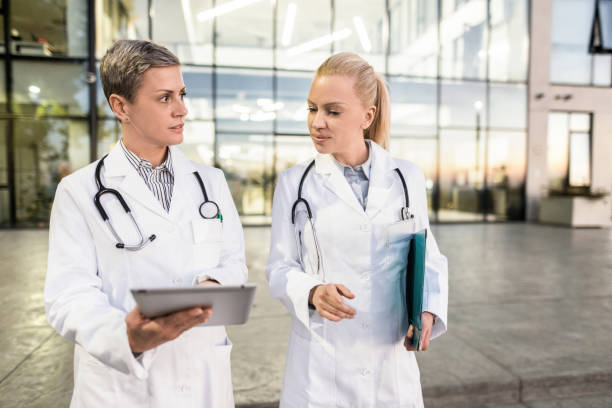 istock Two female doctors using digital tablet in front of hospital building. 1345417925