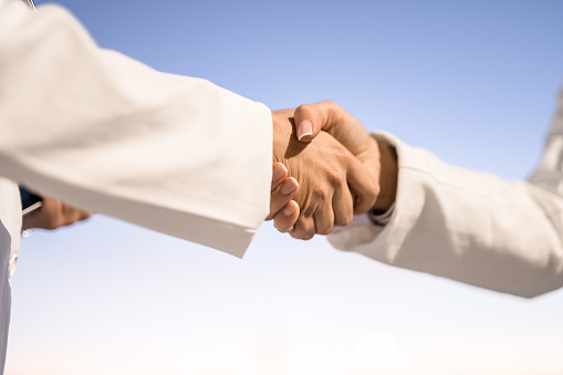 Close-up of two female healthcare workers shaking hands.