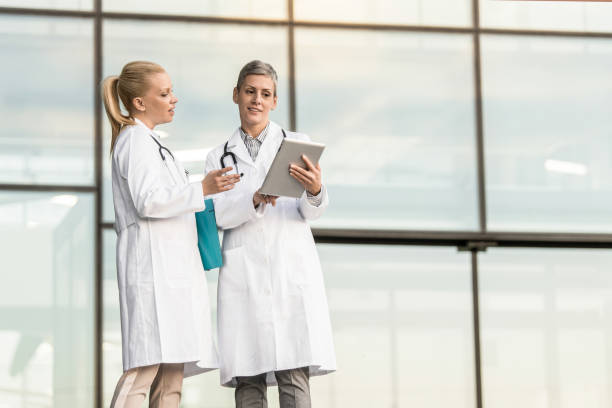 istock Two happy female doctors using digital tablet while standing in front of hospital. 1345418803