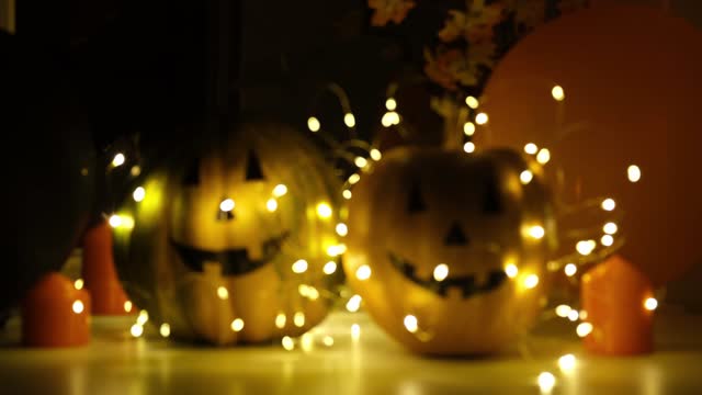 Abstract bokeh background, shining, glowing, blurred gold lights. Bright bokeh from garlands on dark background. Halloween pumpkin decoration, festive backdrop