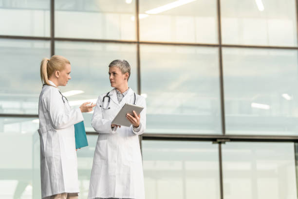 istock Two female doctors using digital tablet while standing in front of hospital. 1345419622