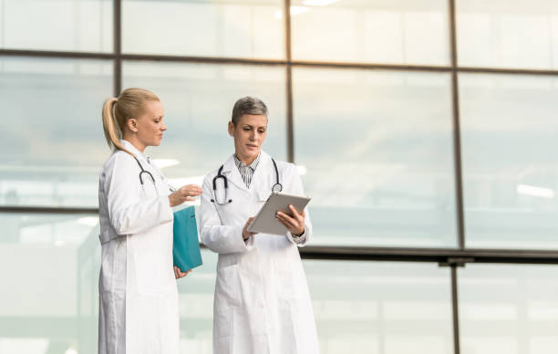 istock Two female doctors using digital tablet while standing in front of hospital. 1345419670
