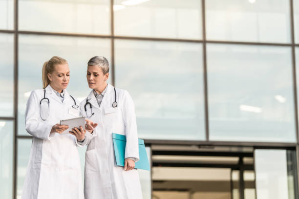 istock Two female doctors using digital tablet while standing in front of hospital. 1345419699