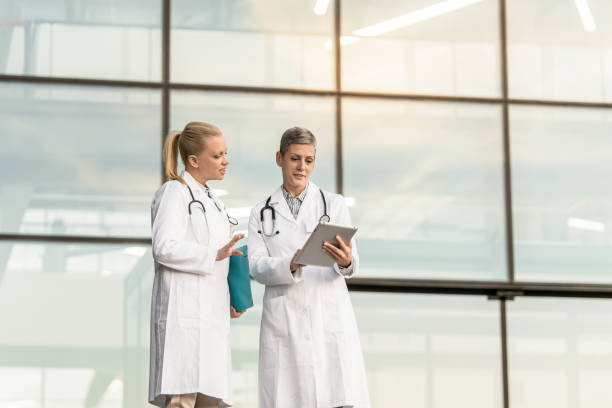 istock Two happy female doctors using digital tablet while standing in front of hospital. 1345419716
