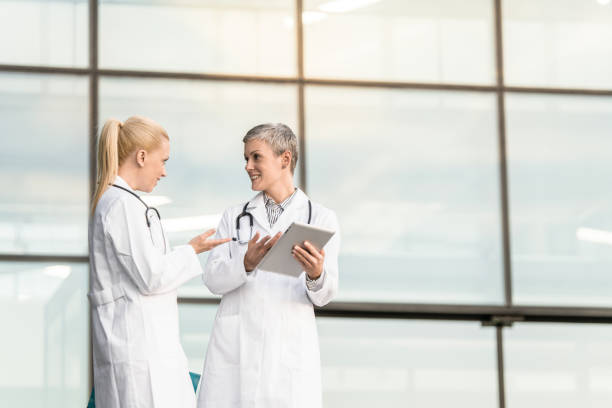 istock Two happy female doctors using digital tablet while standing in front of hospital. 1345419775