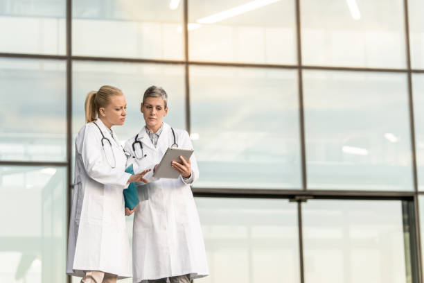 istock Two female doctors using digital tablet while standing in front of hospital. 1345419991