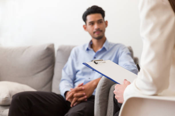 istock Young Asian man talking his problems with professional psychologist while conducting a consultation and making notes to seek advice and therapy 1345430368