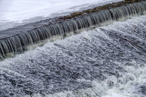 istock A small flat cascade in a calm river with ice in winter. 1345432302
