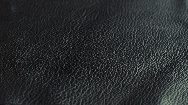 Touching black leather with hand close-up, production handmade accessories made of genuine or artificial leather. Animal skin material on workplace, quality control