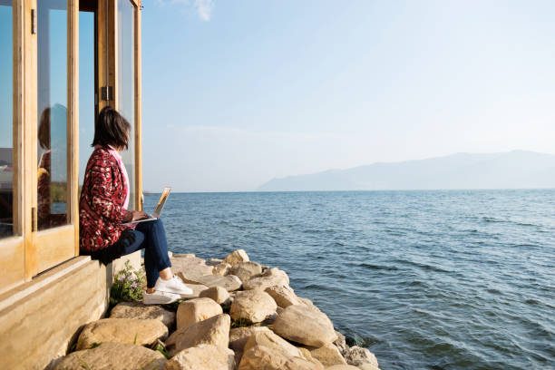 Woman using laptop by the lake.