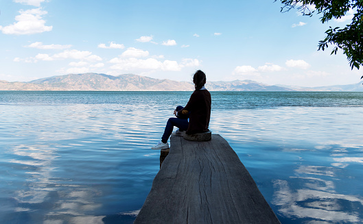 Woman sitting by the lake.