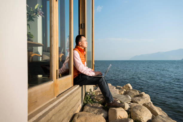 Man using laptop by the lake.