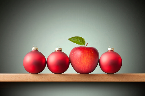 Christmas balls and red apple with leaf on the shelf.