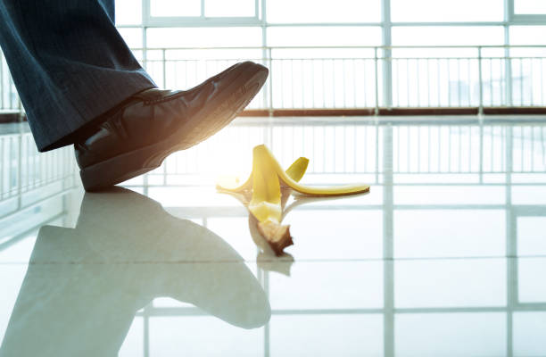 Businessman with a briefcase slipping on a banana peel isolated on white background