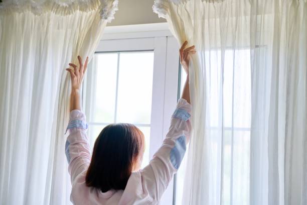 istock Close-up of woman's hand opening and closing light translucent curtains 1345438418