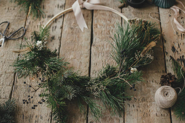 istock Modern christmas wreath with spruce branches, herbs, scissors,candle, pine cones on rustic wood. Moody image. Merry Christmas! Winter holidays preparation. Stylish boho xmas wreath 1345444192