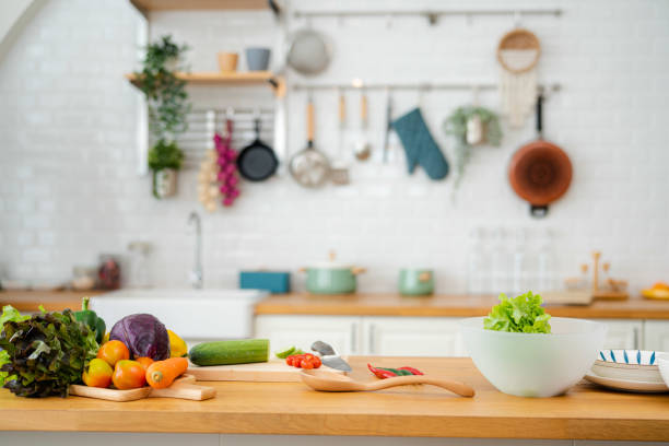 küchentisch mit gemüse und schneidebrett für die zubereitung von salat. - hacken essenszubereitung stock-fotos und bilder