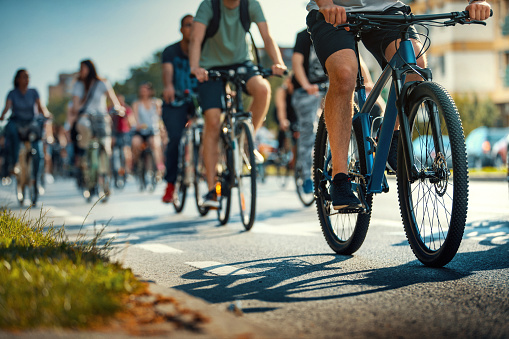 Closeup low angle view of large group of unrecognizable people riding bicycles in city streets and keeping their environment as clean as possible.