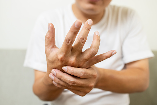 De cerca, hombre asiático de mediana edad con temblor de la enfermedad de Parkinson, síntoma de temblor en reposo, paciente masculino que sostiene su mano para controlar el temblor de las manos, trastornos neurológicos, problemas cerebrales, atención m photo