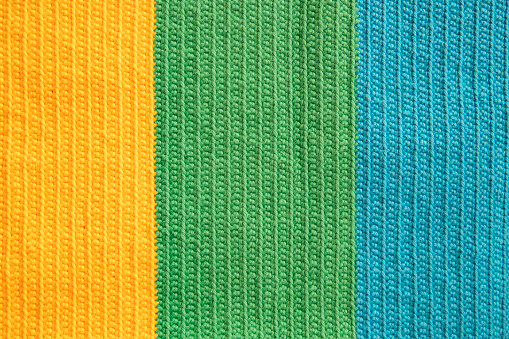 Eye-pleasing crochet pattern in three different soft colors yarn: yellow, green and blue cotton thread, symmetrical background created by the continuous half double stitches as handicraft inspiration.