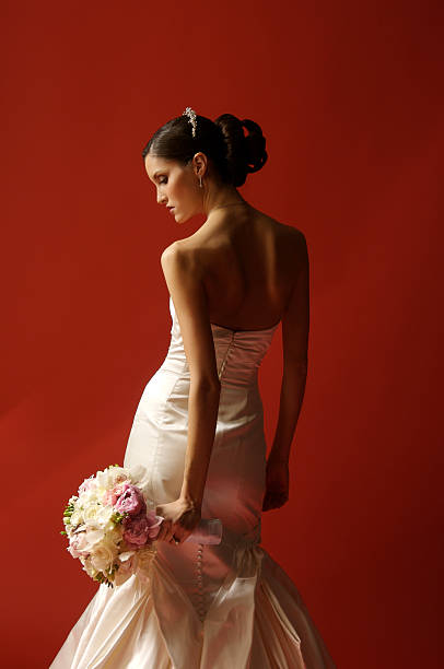 Beautiful bride with bouquet on red background stock photo