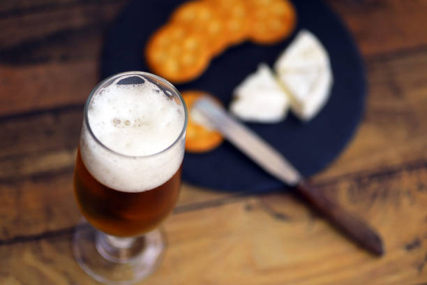 istock Beer poured into a glass, Camembert cheese and crackers 1345452003