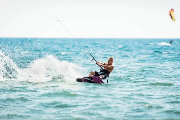 Photo of Athletic man having fun while kitesurfing on the sea.