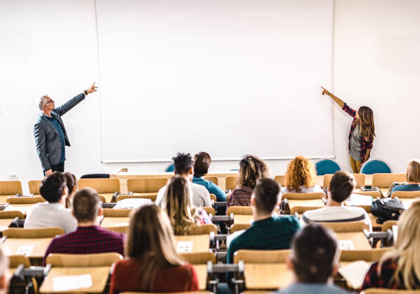 istock Professor and college student giving a lecture in front of whiteboard. 1345454255