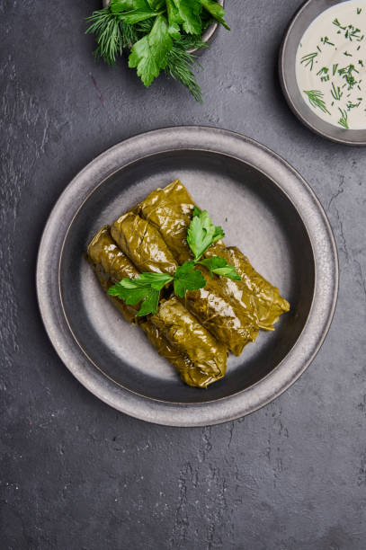 istock Vertical orientation dolma, parsley, saucepan with sour cream on ceramic color graphite plate 1345454361