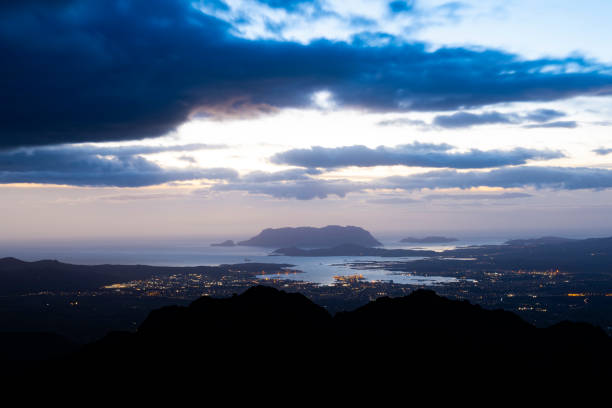 view from above, stunning sunrise during a cloudy day with the city of olbia, the homonymous gulf and tavolara island in the distance. panoramic view from monte pino, sardinia, italy. - city of sunrise bay mountain peak cloud imagens e fotografias de stock