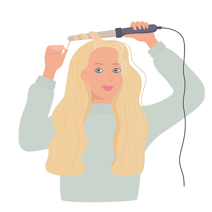 A cute young woman curls her hair with a curling iron. A lady with long blonde hair.